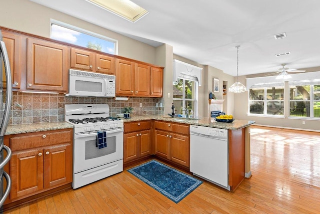 206 Whispering Wind Dr, Georgetown, TX 78633 - kitchen featuring white appliances, light wood finished floors, decorative backsplash, and a peninsula