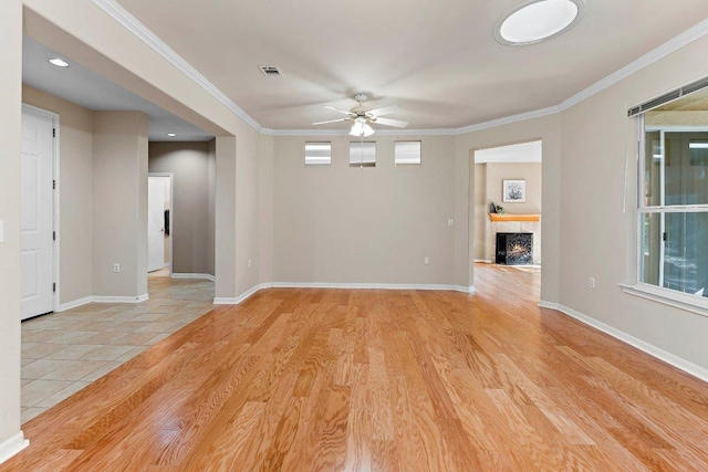206 Whispering Wind Dr, Georgetown, TX 78633 - empty room featuring ceiling fan, a tiled fireplace, light wood-style floors, crown molding, and baseboards