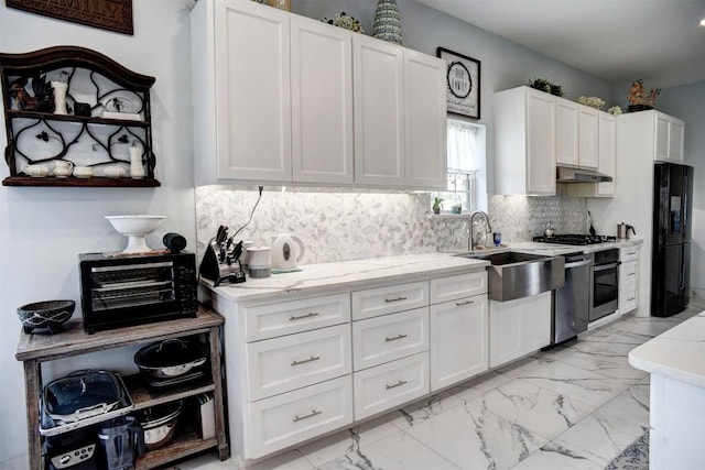 626 Sparta Field Rd, Waelder, TX 78959 - kitchen with freestanding refrigerator, stainless steel oven, white cabinets, decorative backsplash, and under cabinet range hood