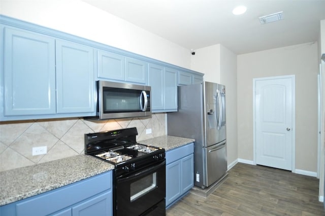 11024 Night Camp Dr, Austin, TX 78754 - kitchen featuring stainless steel appliances, backsplash, wood finished floors, baseboards, and light stone countertops