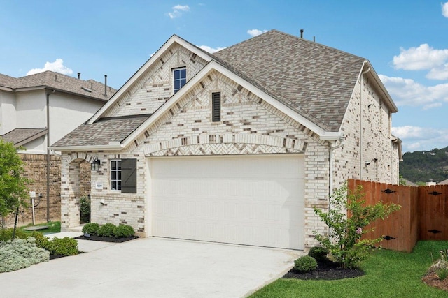 8119 Purple Aster Pass, Leander, TX 78645 - french country style house featuring concrete driveway, a garage, a shingled roof, and brick siding