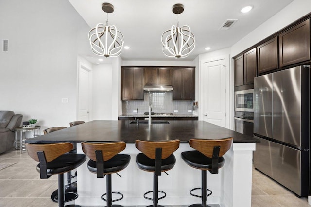 8119 Purple Aster Pass, Leander, TX 78645 - kitchen with appliances with stainless steel finishes, decorative backsplash, a chandelier, dark brown cabinetry, and a breakfast bar area