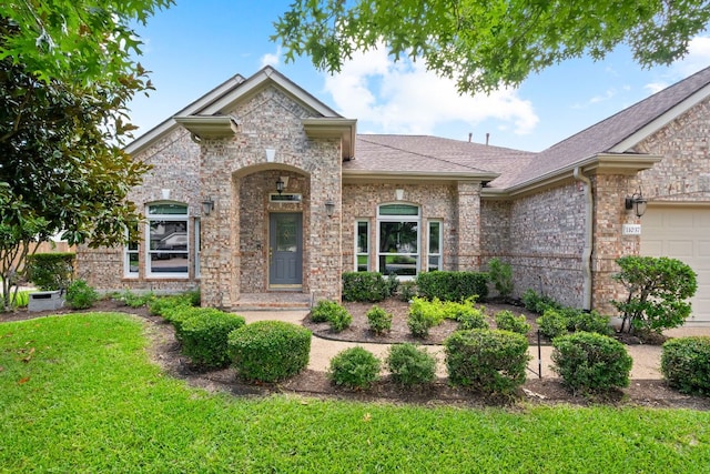 11037 River Plantation Dr, Austin, TX 78747 - french country home featuring brick siding, a front lawn, a shingled roof, and an attached garage