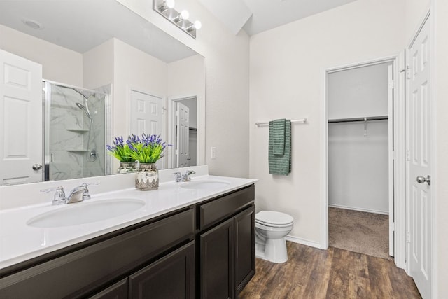 709 Hummingbird Ln, Leander, TX 78641 - full bath with a marble finish shower, double vanity, a walk in closet, toilet, and wood finished floors