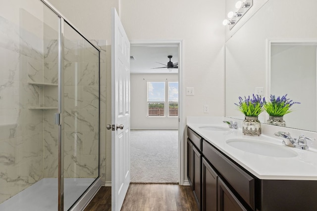 709 Hummingbird Ln, Leander, TX 78641 - bathroom featuring ceiling fan, double vanity, a marble finish shower, wood finished floors, and baseboards