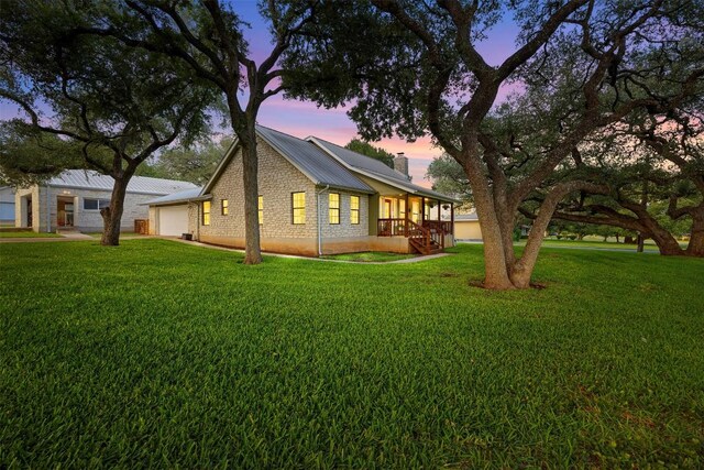 208 Willet Dr, Buda, TX 78610 - property exterior at dusk featuring a chimney, an attached garage, a yard, and brick siding