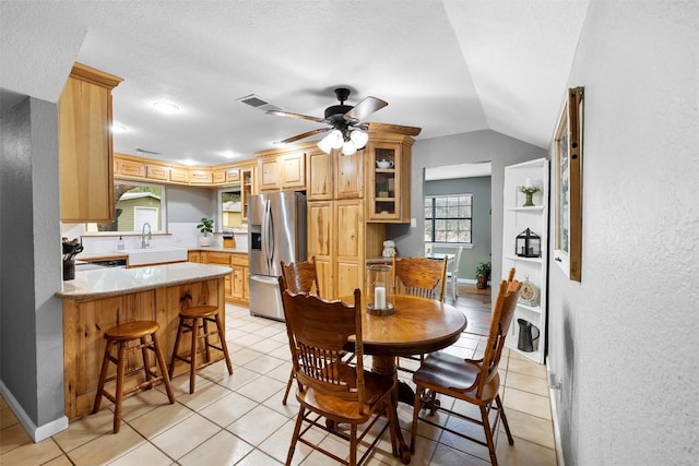 208 Willet Dr, Buda, TX 78610 - dining space with ceiling fan, light tile patterned floors, vaulted ceiling, baseboards, and a textured wall