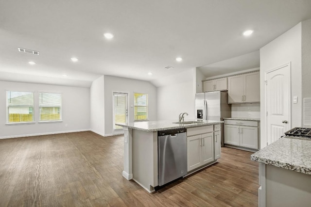 210 Briggs Ln, San Marcos, TX 78666 - kitchen with appliances with stainless steel finishes, dark wood-type flooring, a center island with sink, light stone counters, and recessed lighting