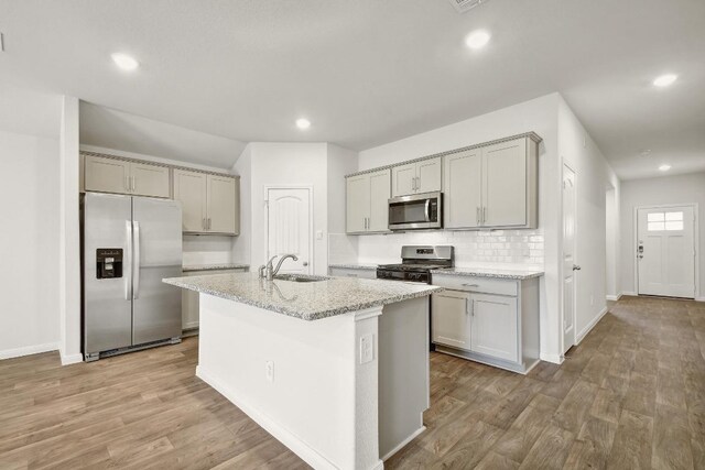210 Briggs Ln, San Marcos, TX 78666 - kitchen with stainless steel appliances, gray cabinets, a sink, decorative backsplash, and light wood-style floors