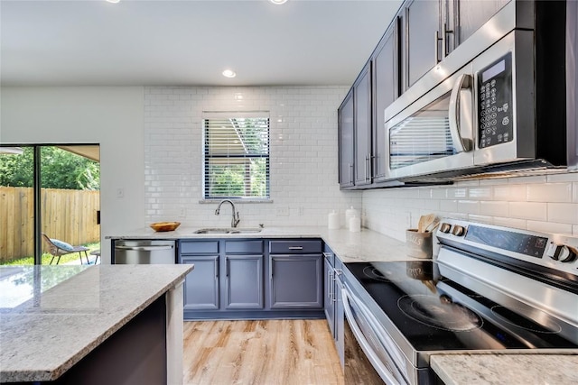 14605 Naruna Way, Pflugerville, TX 78660 - kitchen featuring appliances with stainless steel finishes, a sink, backsplash, light wood finished floors, and recessed lighting