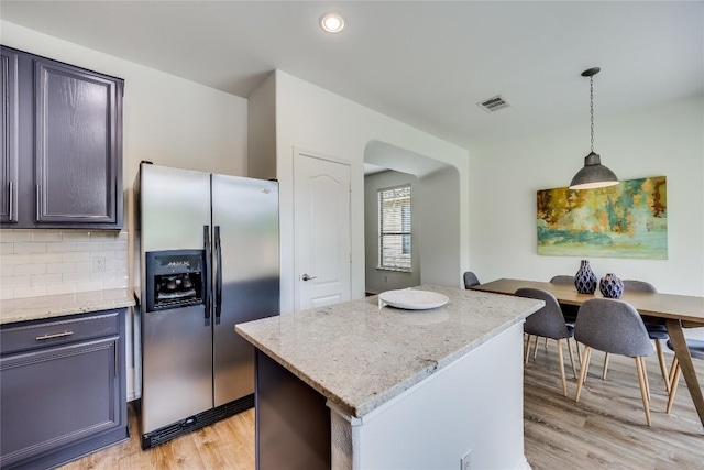 14605 Naruna Way, Pflugerville, TX 78660 - kitchen featuring stainless steel fridge with ice dispenser, light wood finished floors, decorative light fixtures, light stone counters, and decorative backsplash