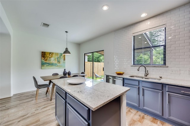 14605 Naruna Way, Pflugerville, TX 78660 - kitchen with a sink, dishwasher, light wood finished floors, light stone counters, and a center island