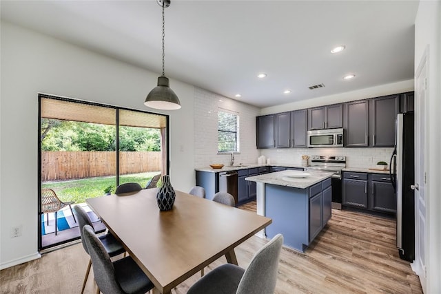 14605 Naruna Way, Pflugerville, TX 78660 - kitchen featuring stainless steel appliances, a kitchen island, a sink, light wood-style floors, and decorative backsplash