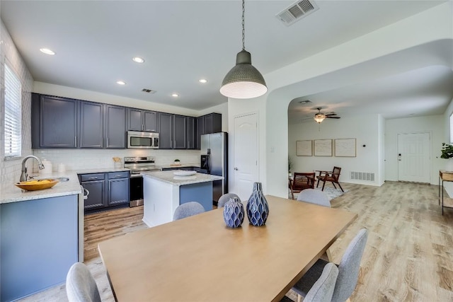 14605 Naruna Way, Pflugerville, TX 78660 - kitchen featuring stainless steel appliances, a sink, a center island, tasteful backsplash, and light wood-style flooring