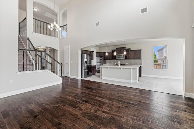 505 Fair Oaks Dr, Georgetown, TX 78628 - unfurnished living room with light wood finished floors, a sink, a chandelier, stairs, and a towering ceiling