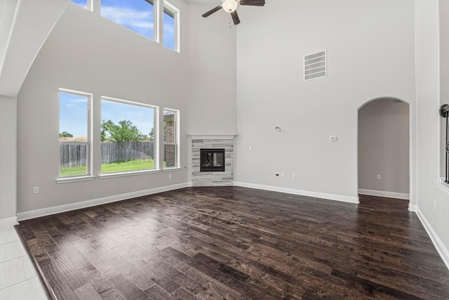 505 Fair Oaks Dr, Georgetown, TX 78628 - unfurnished living room featuring a high ceiling, ceiling fan, wood finished floors, arched walkways, and a glass covered fireplace