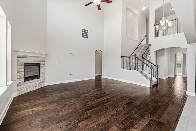 505 Fair Oaks Dr, Georgetown, TX 78628 - unfurnished living room with a towering ceiling, arched walkways, a chandelier, a ceiling fan, and wood-type flooring