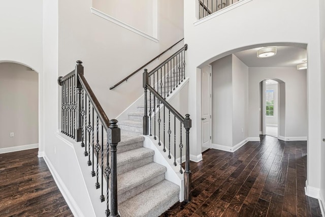 505 Fair Oaks Dr, Georgetown, TX 78628 - staircase featuring hardwood / wood-style flooring, baseboards, arched walkways, and a towering ceiling