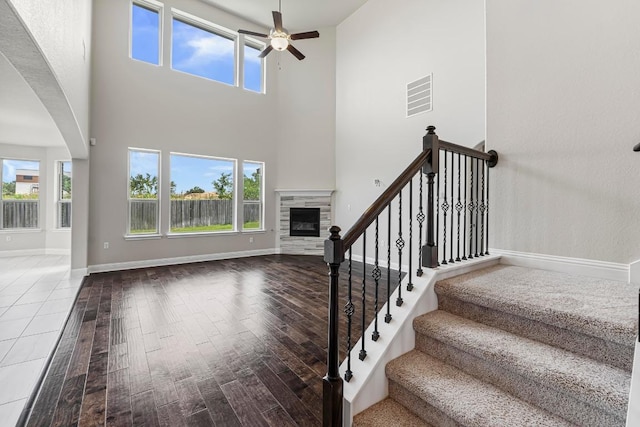505 Fair Oaks Dr, Georgetown, TX 78628 - unfurnished living room featuring a ceiling fan, wood finished floors, a glass covered fireplace, a high ceiling, and baseboards