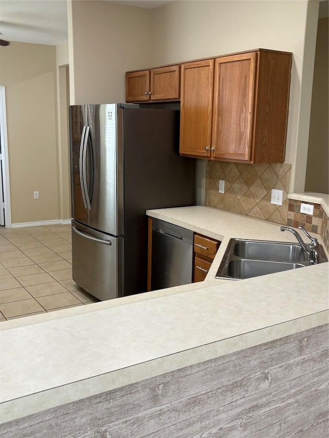 127 Nassau Cir, Georgetown, TX 78633 - kitchen with stainless steel appliances, light countertops, tasteful backsplash, brown cabinetry, and light tile patterned floors