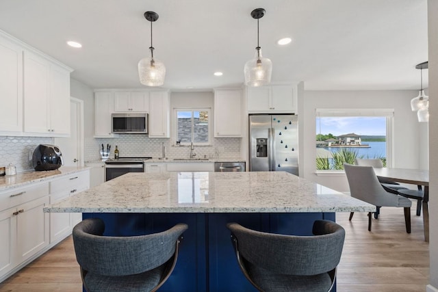 515 Circle Dr, Sunrise Beach, TX 78643 - kitchen with appliances with stainless steel finishes, a sink, tasteful backsplash, a kitchen bar, and white cabinetry