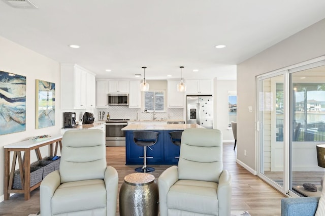 515 Circle Dr, Sunrise Beach, TX 78643 - kitchen with stainless steel appliances, white cabinets, light wood finished floors, backsplash, and recessed lighting