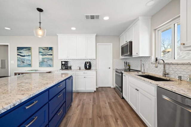 515 Circle Dr, Sunrise Beach, TX 78643 - kitchen with stainless steel appliances, a sink, blue cabinetry, white cabinetry, and recessed lighting