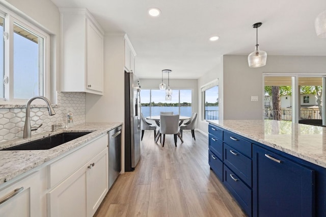 515 Circle Dr, Sunrise Beach, TX 78643 - kitchen featuring appliances with stainless steel finishes, blue cabinetry, a sink, light wood finished floors, and white cabinetry