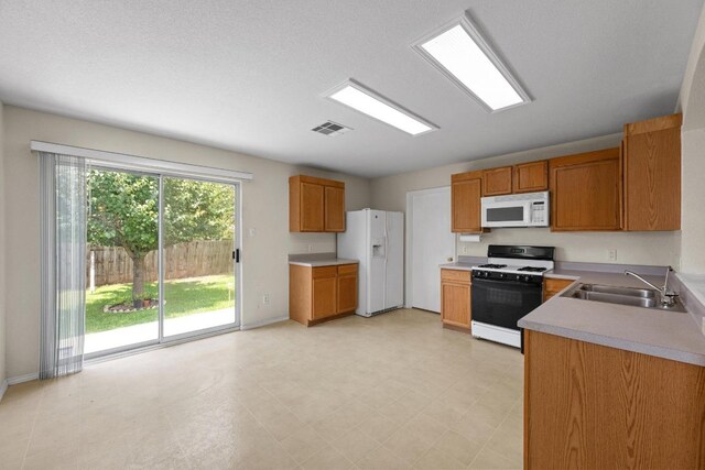 3807 Haleys Way, Round Rock, TX 78665 - kitchen with white appliances, a sink, brown cabinetry, light countertops, and light floors