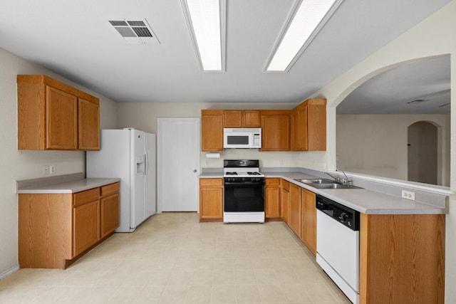 3807 Haleys Way, Round Rock, TX 78665 - kitchen featuring white appliances, a sink, arched walkways, light countertops, and a peninsula
