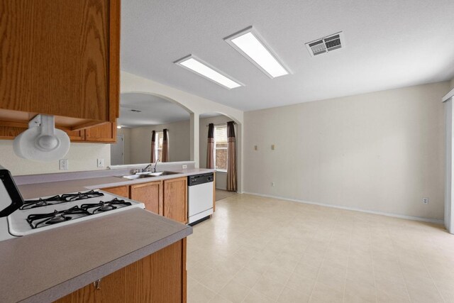 3807 Haleys Way, Round Rock, TX 78665 - kitchen featuring white dishwasher, a sink, arched walkways, gas range, and light countertops