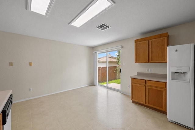 3807 Haleys Way, Round Rock, TX 78665 - kitchen featuring white fridge with ice dispenser, brown cabinets, and light countertops