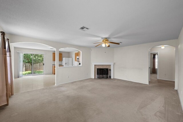 3807 Haleys Way, Round Rock, TX 78665 - unfurnished living room with a ceiling fan, light colored carpet, a tile fireplace, and arched walkways