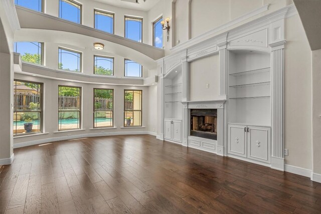 800 Canyon Bend Rd, Pflugerville, TX 78660 - unfurnished living room featuring healthy amount of natural light, a fireplace, dark wood-type flooring, a towering ceiling, and baseboards