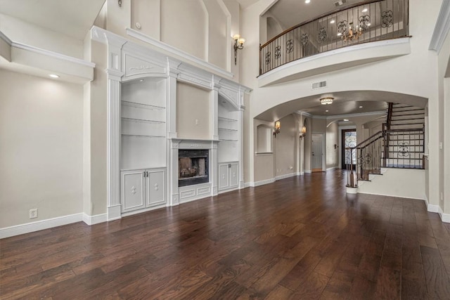 800 Canyon Bend Rd, Pflugerville, TX 78660 - unfurnished living room with wood finished floors, a towering ceiling, a fireplace, baseboards, and arched walkways