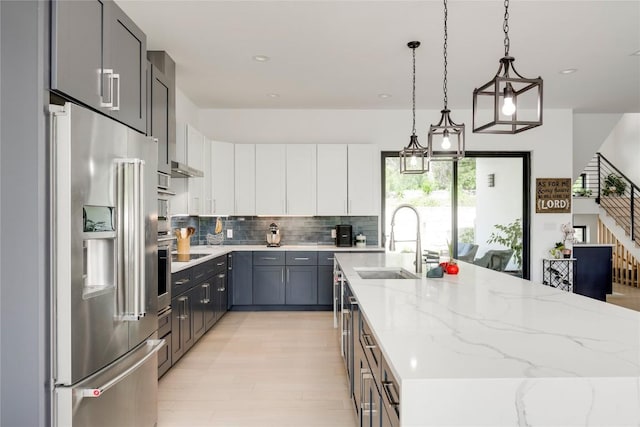 13209 Mansfield Dr, Austin, TX 78732 - kitchen featuring high quality fridge, decorative backsplash, light stone counters, a kitchen island with sink, and pendant lighting