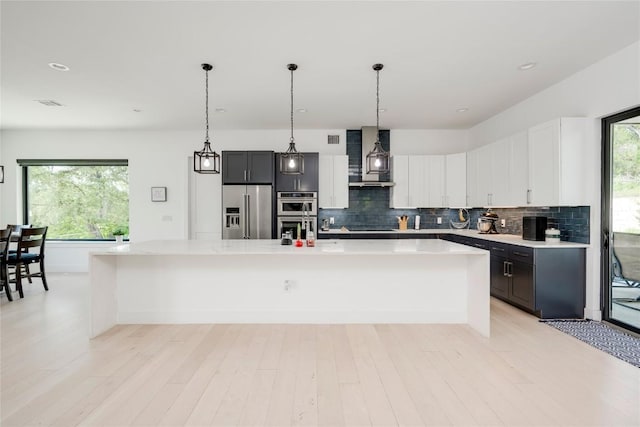 13209 Mansfield Dr, Austin, TX 78732 - kitchen with appliances with stainless steel finishes, light countertops, tasteful backsplash, a large island with sink, and recessed lighting