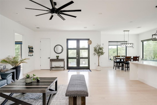 13209 Mansfield Dr, Austin, TX 78732 - living area featuring light wood-type flooring, a ceiling fan, a chandelier, and french doors