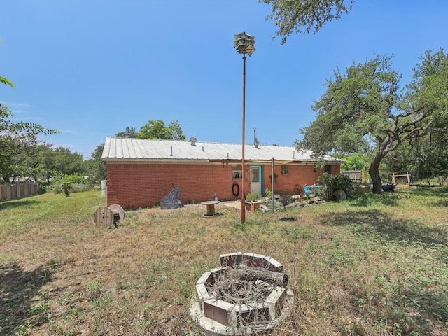 8622 Thunderbird Rd, Austin, TX 78736 - back of property featuring an outdoor fire pit, metal roof, and brick siding