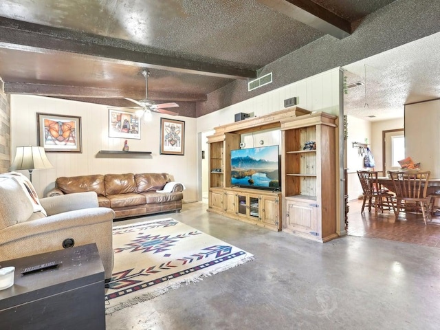 8622 Thunderbird Rd, Austin, TX 78736 - living room with beam ceiling, a ceiling fan, concrete flooring, wooden walls, and a textured ceiling