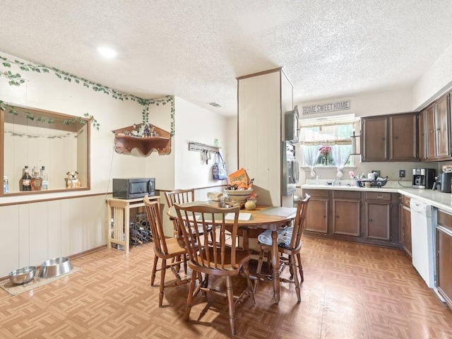 8622 Thunderbird Rd, Austin, TX 78736 - kitchen featuring black microwave, a textured ceiling, light countertops, white dishwasher, and dark brown cabinets