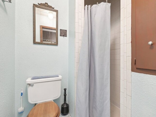 8622 Thunderbird Rd, Austin, TX 78736 - bathroom featuring curtained shower, toilet, and a textured wall