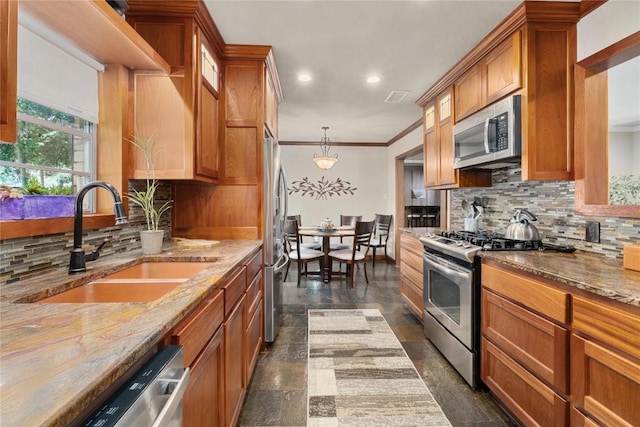 2301 Del Curto Rd, Austin, TX 78704 - kitchen featuring stainless steel appliances, a sink, brown cabinets, light stone counters, and crown molding