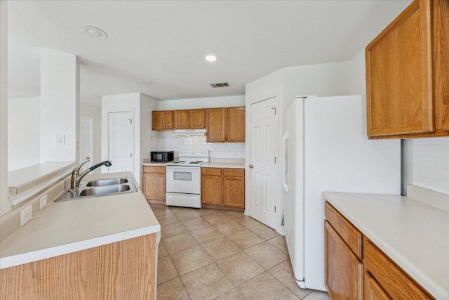110 Rinehardt St, Hutto, TX 78634 - kitchen with white appliances, a sink, under cabinet range hood, backsplash, and brown cabinetry
