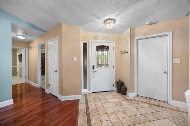13210 Dime Box Trl, Austin, TX 78729 - entrance foyer with baseboards, a textured ceiling, a chandelier, and light wood-type flooring