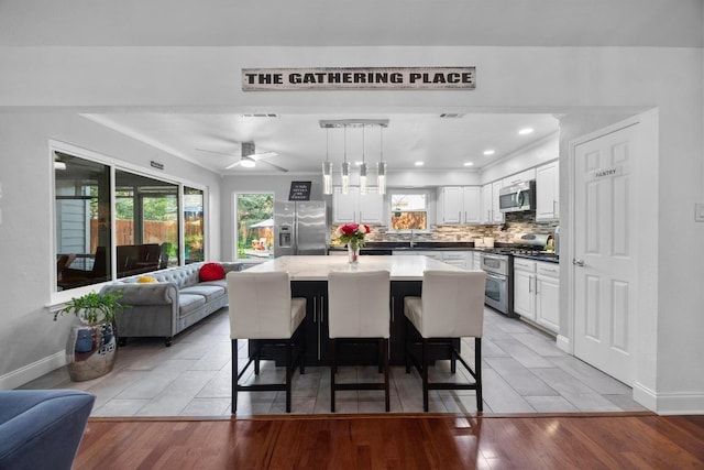 13210 Dime Box Trl, Austin, TX 78729 - kitchen featuring stainless steel appliances, open floor plan, white cabinetry, backsplash, and a kitchen island