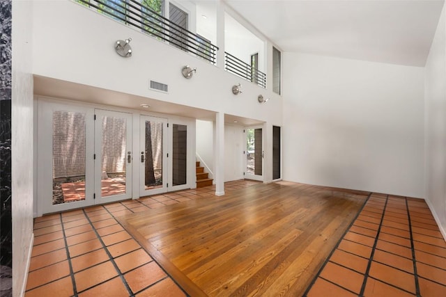 5902 Tumbling Cir, Austin, TX 78731 - unfurnished living room featuring stairs, a towering ceiling, and wood finished floors