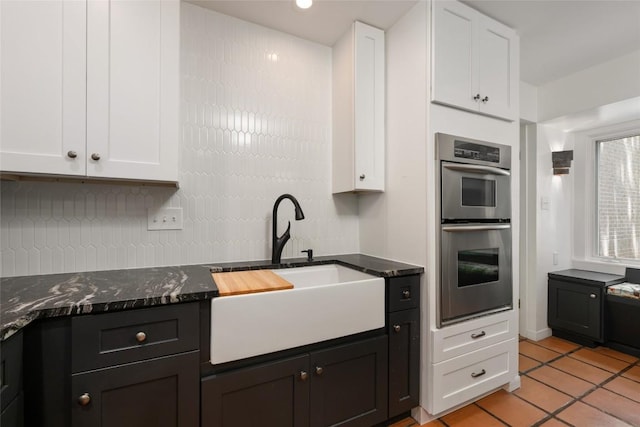 5902 Tumbling Cir, Austin, TX 78731 - kitchen featuring a sink, double oven, white cabinetry, dark stone countertops, and light tile patterned floors