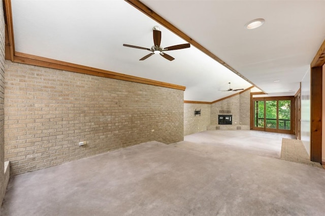 5902 Tumbling Cir, Austin, TX 78731 - unfurnished living room with a ceiling fan, brick wall, vaulted ceiling, and a glass covered fireplace