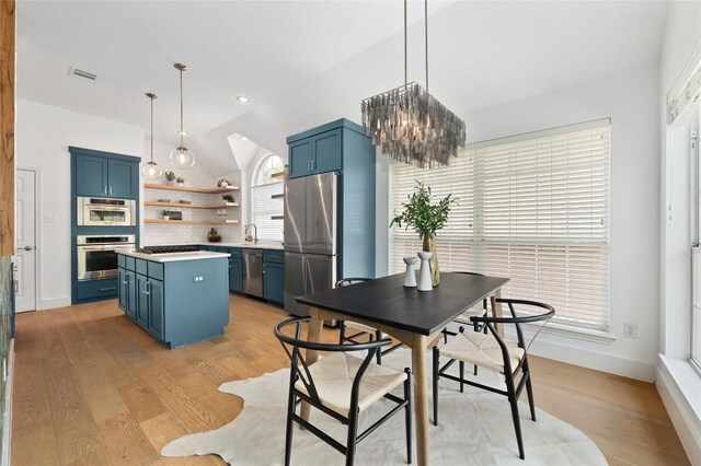 10239 Scull Creek Dr, Austin, TX 78730 - kitchen with appliances with stainless steel finishes, blue cabinetry, open shelves, lofted ceiling, and a kitchen island